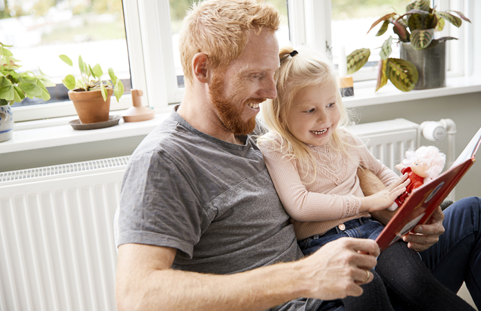 Far og datter sidder og læser foran radiator