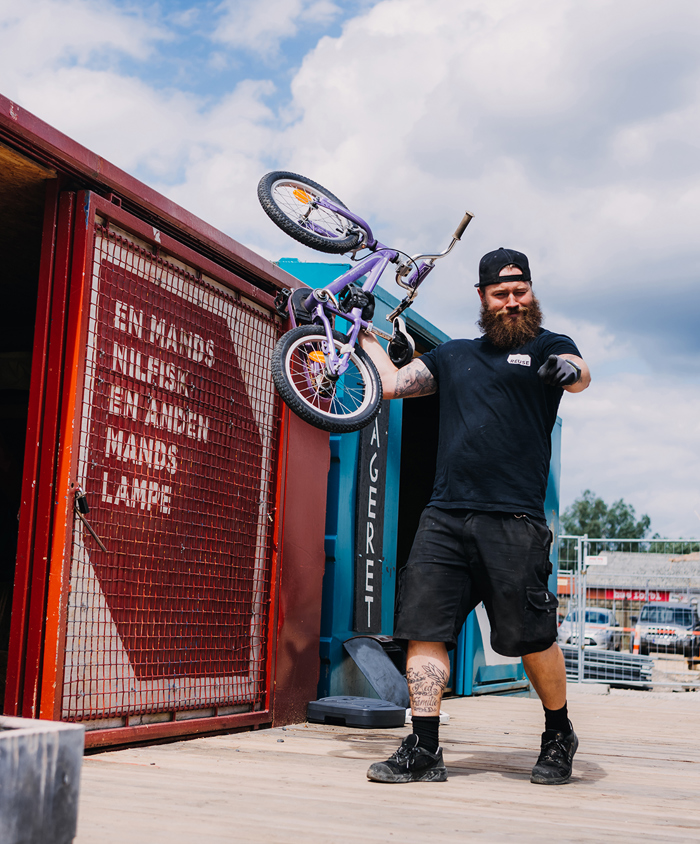 Medarbejder på REUSE bærer børnecykel ind i container