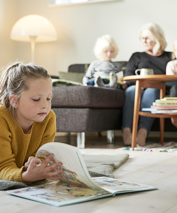 Pige ligger og læser på stuegulvet 