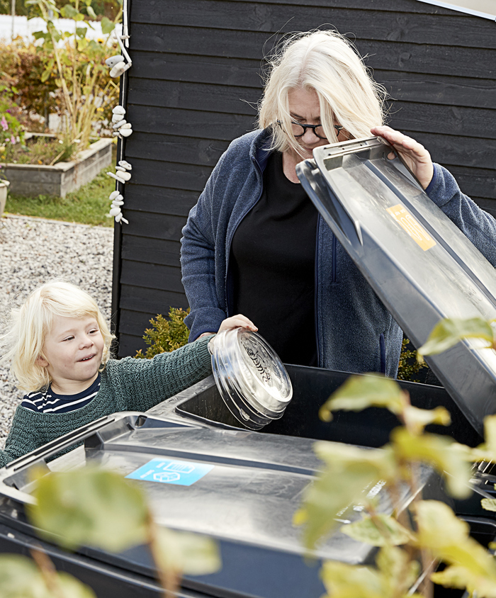 Bedstemor og barn putter plast i beholderen til genanvendeligt affald.